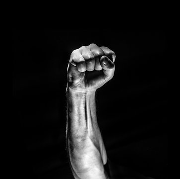 strong male man raised fist on a black background, power, war, protest, fist ready to fight
