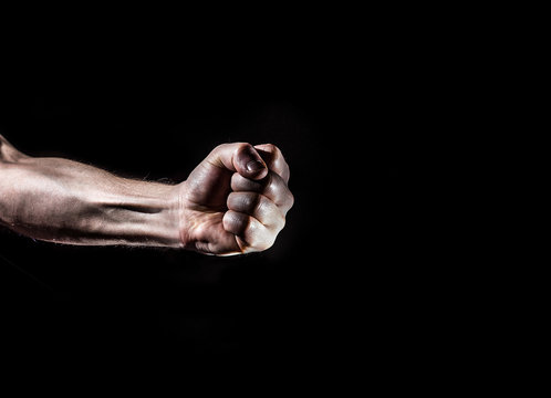 strong male man raised fist on a black background, power, war, protest, fist ready to fight