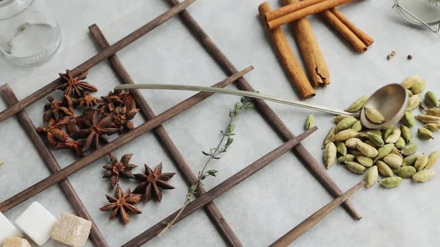 Spices and ingredients for aromatic sweet hot drinks - anise or aniseed, cinnamon bark, cardamom seeds, cane sugar and white sugar cbes, thyme twig. Slow pan.