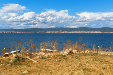 Black Sea coast. Coastline with dry yellow grass. Bay View. Sunny Beach, mountains and houses on the horizon. Blue sky with cumulus clouds.
