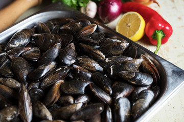 Fresh mussels with ingredients for cooking on rustic background, top view, border. Seafood concept.