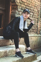 Girl dressed in urban clothes posing in the city surroundings surrounded by modern culture and...