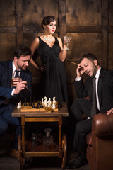 Handsome executive rich men playing chess in restaurant. Men spending free time in restaurant and thinking about business.