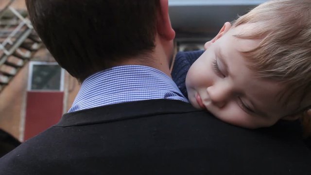 Little boy sleeping on dad's shoulder