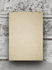 Blank brown canvas frame hanged by pegs against gray wall