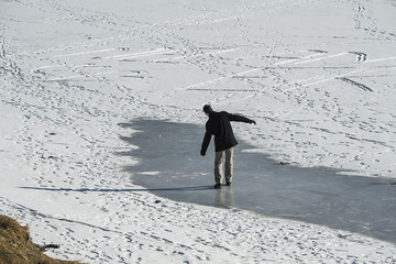 Mann sucht Gleichgewicht auf dem zugefrorenen Tannalpsee,  Melchsee-Frutt, Obwalden, Schweiz