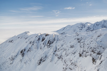 Aerial shot of snowy mountain range on a sunny winter day