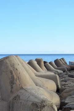 M&auml;chtige Tetrapoden am Ufer zur Befestigung und zum Schutz der K&uuml;ste, im Hintergrund das Meer, vor tiefblauem Himmel