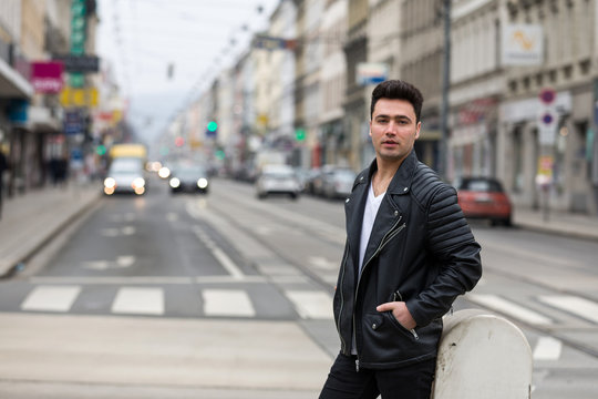Handsome young man with black leather jacket on street