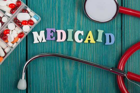 Text "Medicaid" of colored wooden letters, stethoscope and pills