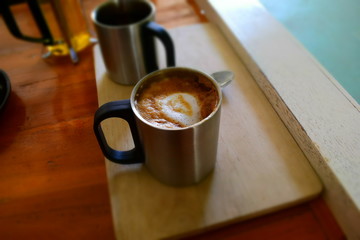 Hot dark coffee in stainless cup with cup of hot tea and stainless spoon on the wood. Dark coffee concept.