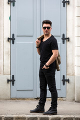 Handsome young man with jeans and leather jacket over his shoulder