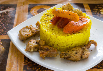 yellow rice with turmeric with fried rabbit meat and vegetables on square plate