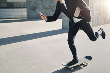 Businessman on a skateboard checking his phone