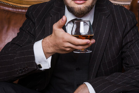 Closeup of senior man sitting at the table having a glass of cognac