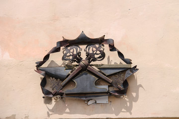 Metal heraldic sign with two crossed keys on a building wall. Mukachevo, Ukraine