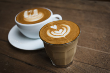 Hot glass of coffee on wooden table in the coffee shop.