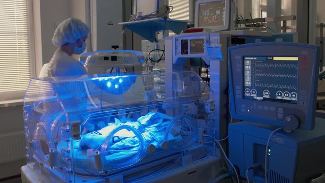 Doctor comes to an infant incubator with little patient