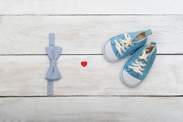 shoes and a butterfly-tie for a young boy on a wooden background.