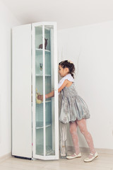 Fototapeta na wymiar Young child girl opening cupboard door
