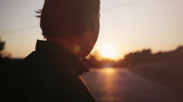 Portrait of a lonely man, drinking beer outdoor looks at sunset sun flare effects. 1920x1080