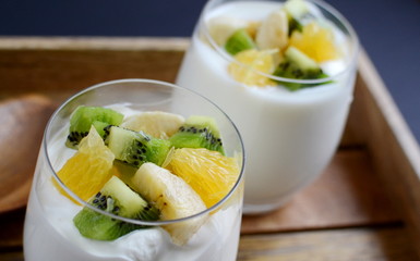 Fresh colorful vitamin breakfast yogurt pieces fruits kiwi banana orange in glass cups