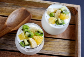 Fresh colorful vitamin breakfast yogurt pieces fruits kiwi banana orange in glass cups