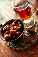 Bowl of dried dates on old wooden table with tea