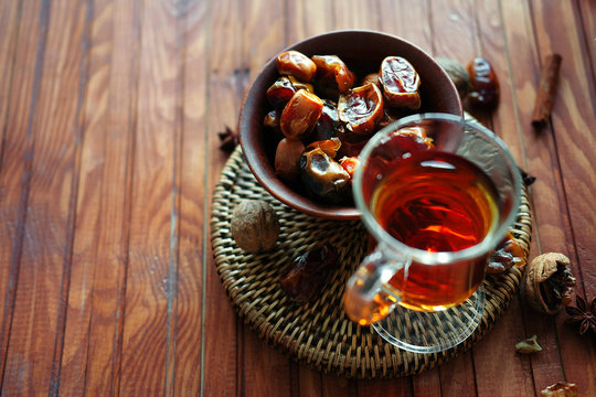 Bowl of dried dates on old wooden table with tea