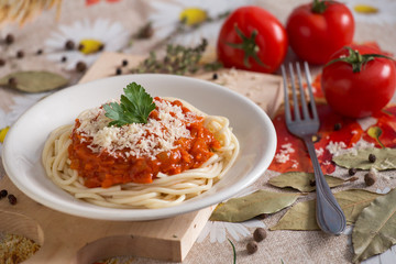 spaghetti on a white plate with a sauce of carrots, onions and tomato paste with cheese