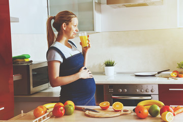 pregnant woman on kitchen drinking healthy fruit juice