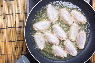 Chef frying chicken wings in pan