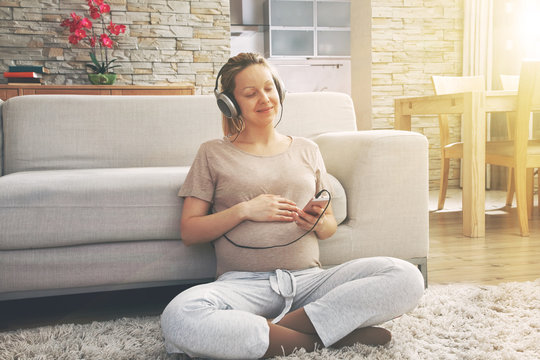 happy pregnant woman listening to music in headphones