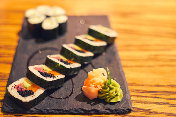 Blurred japanese sushi rolls with wasabi sauce and marinated ginger petals on stone granite background. Japanese food restaurant. Bokeh basic background for design                               