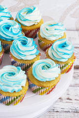 Festive cupcakes with cream in blue on a white wooden background