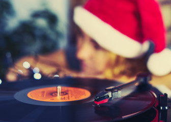 Blurred Image of Christmas. Gramophone playing a record. Blurred a girl in a Christmas cap with red hair listening to a vinyl record in the background   