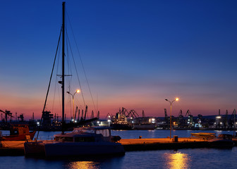 Sea port. Evening panorama. Yacht at sea pier on the background of a bright sunset. Bright background for the basic design