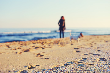 Blurred sea views. Blurred young woman walking a dog breed Jack Russell on the seashore. Basic background for design
