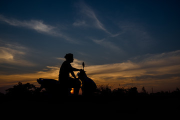 Silhouette of a man sitting on a motorcycle. Sunset