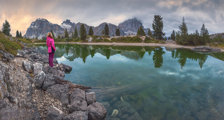 Female hiker standing next to the idyllic mountain lake