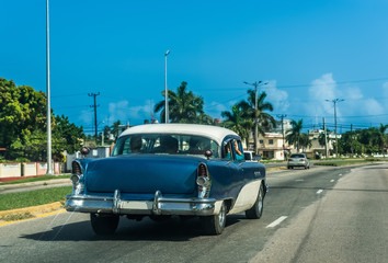 Blauer amerikanischer Oldtimer mit weißem Dach fährt durch Varadero Kuba - Serie Kuba Reportage