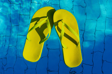 yellow flip-flops floating in a swimming pool, a top view