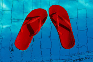 red flip-flops floating in a swimming pool, a top view