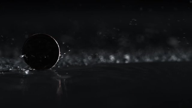 US currency, quarter (25 cents) coin spinning on water surface. Shot with high speed camera, phantom flex 4K. Slow Motion.