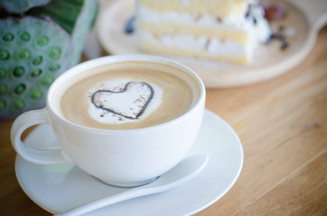 Closeup offee cup with heart shape latte art on wood table