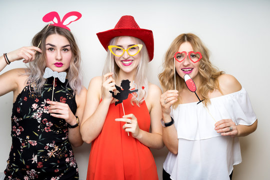 three happy young ladies girls strike a pose on white background photo booth with party props