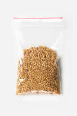 Plastic transparent zipper bag with half raw flax seeds cereal isolated on white, Vacuum package mockup with red clip. Concept.