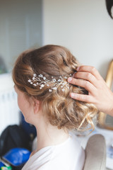 Fototapeta premium Hairdresser makes wedding hairstyle bride with blond hair