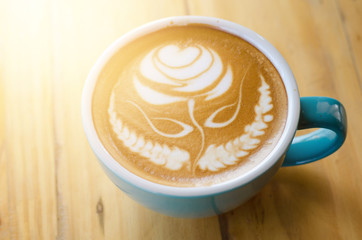 hot coffee with foam milk art rose on wooden table