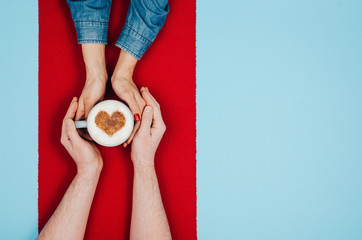 Couple in love holding hands with coffee on colorful table. Photograph taken from above, top view with copy space